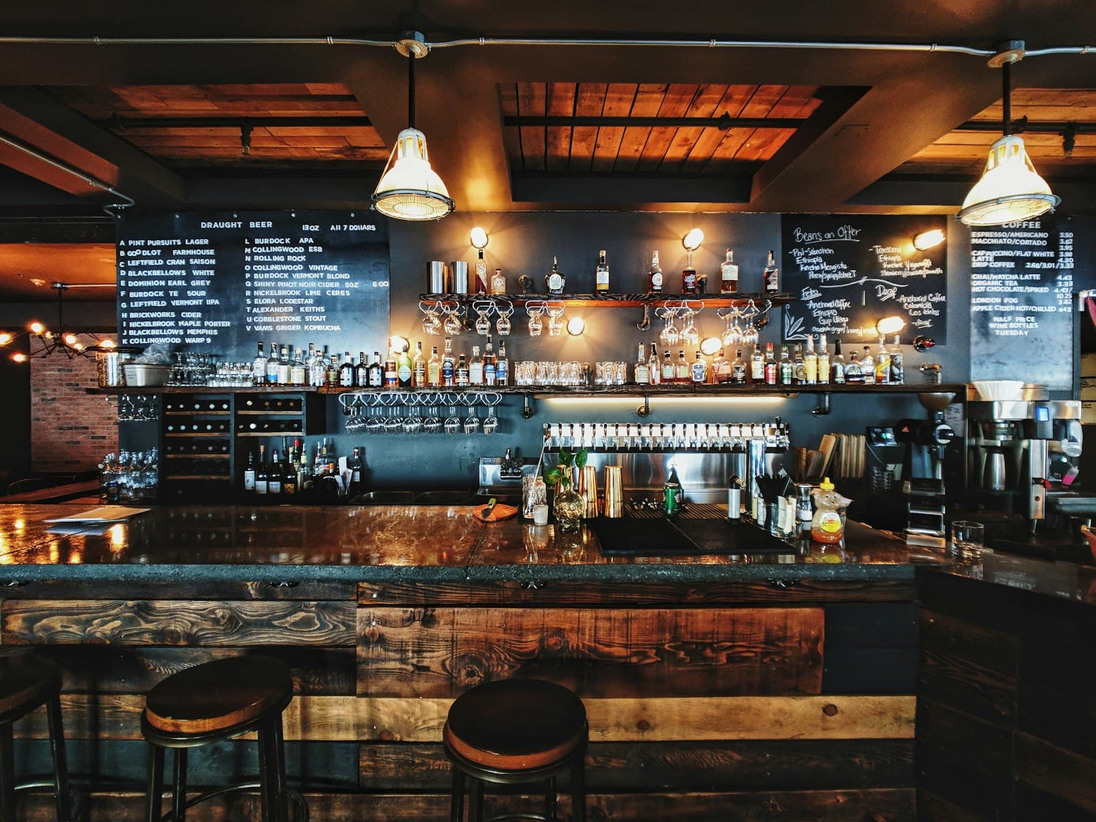 Warmly lit bar with chalkboard menus and rows of bottles