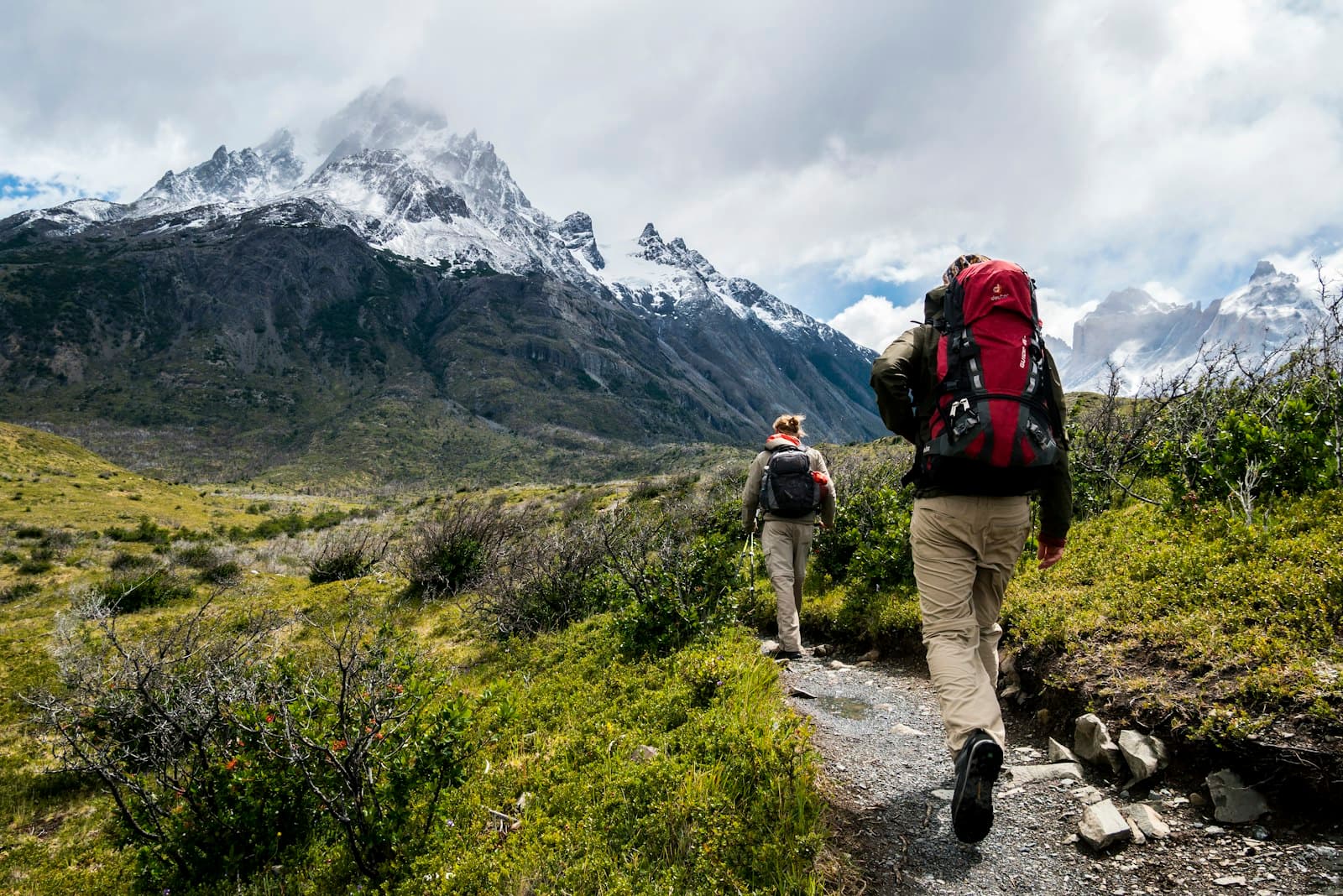 Two hikers on a trail beneath snow-capped peaks in Patagonia