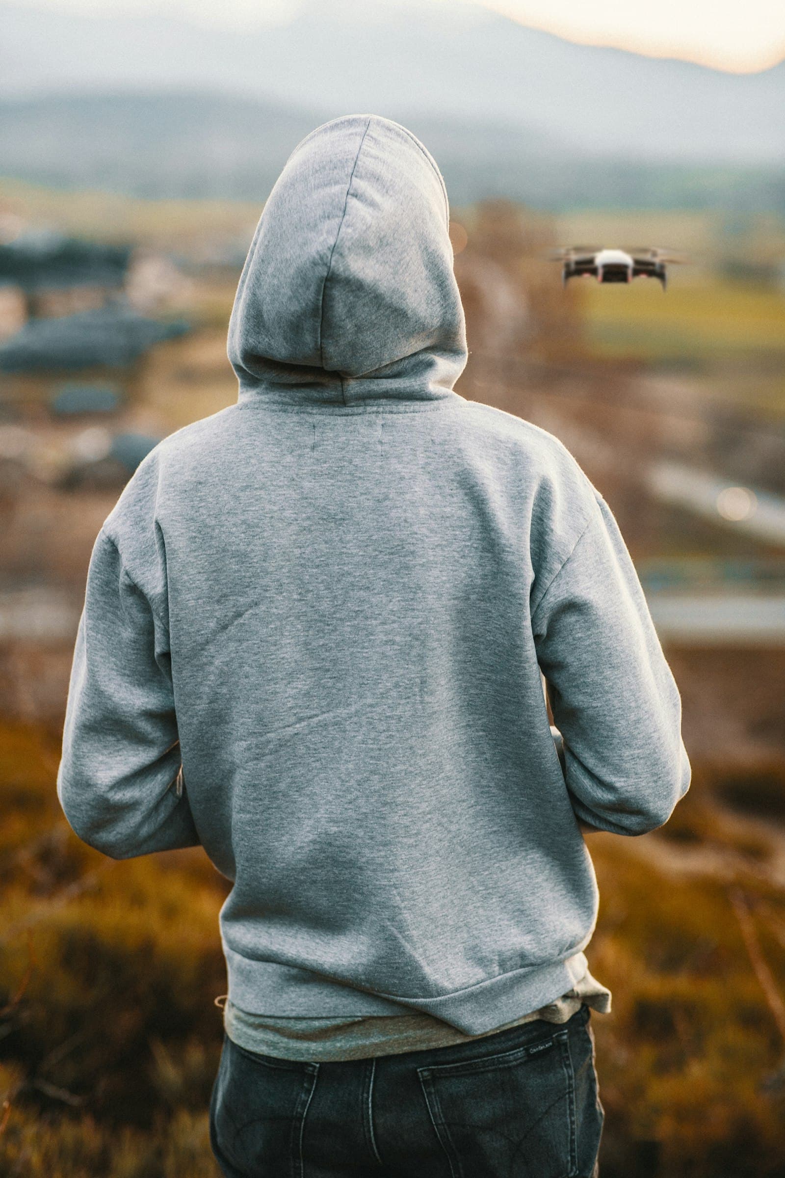 Figure in a grey hoodie seen from behind in an open field