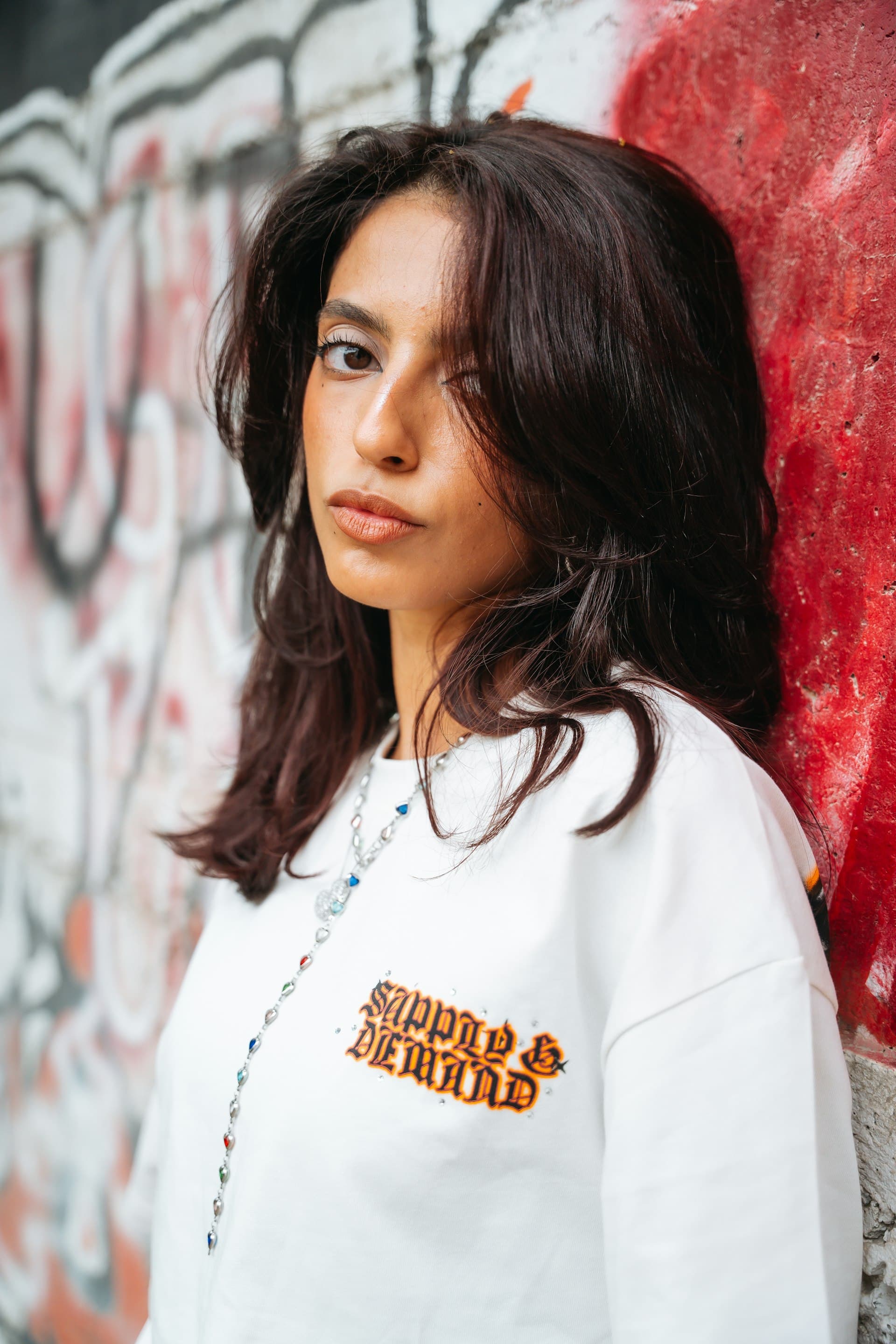 Young woman in white sweatshirt against graffiti wall